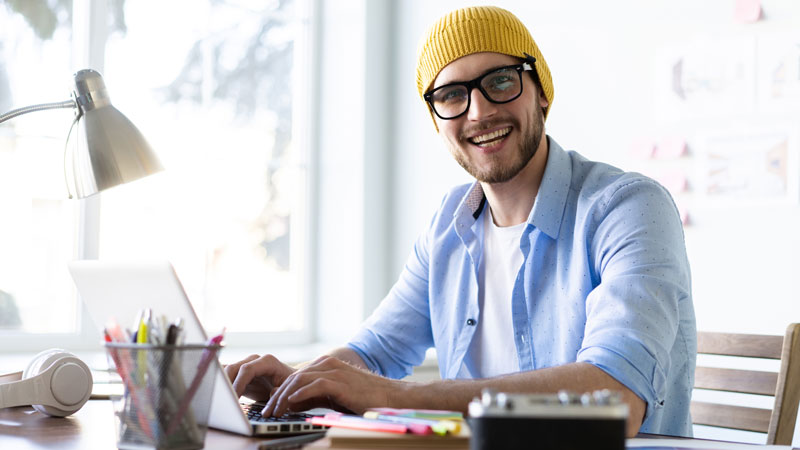 jovem sentado a uma secretária com um computador à frente